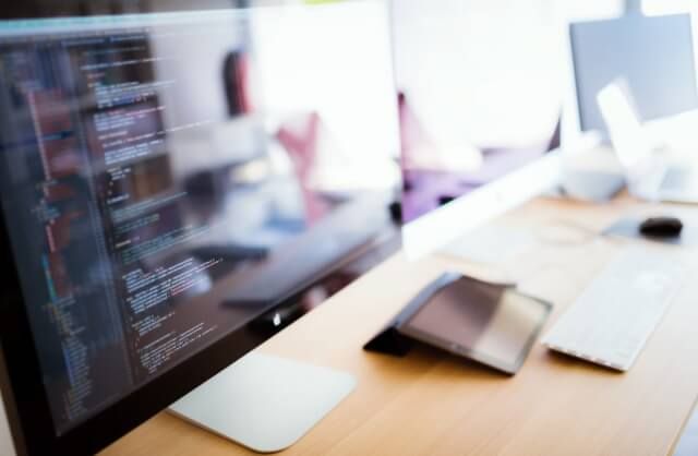 プログラムのコードが表示されたパソコンの作業風景